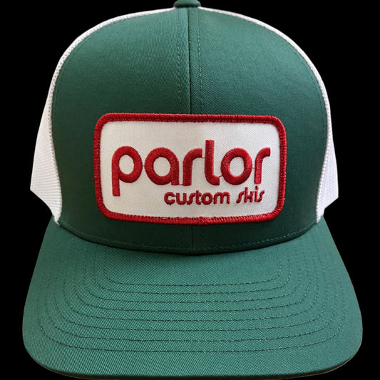 A green and white trucker hat with a red and white 'parlor custom skis' patch on the front.